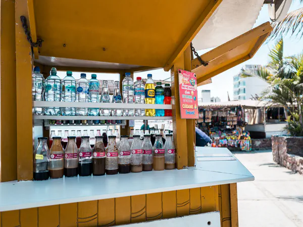 Puesto de bebidas de un mercado en Huanchaco, Perú, con botellas ordenadas en los estantes